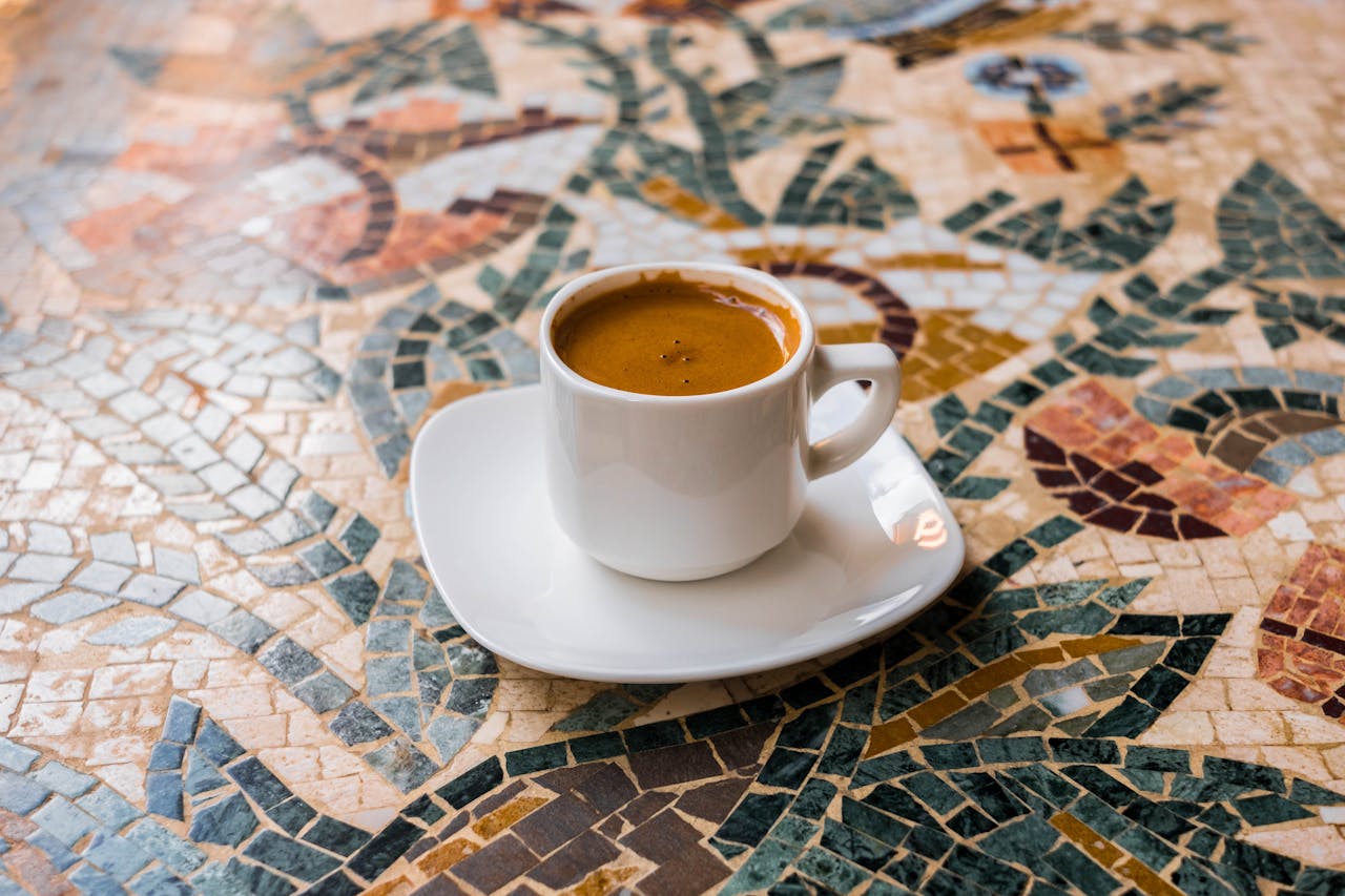 White espresso cup on a vibrant mosaic table, perfect for coffee enthusiasts.